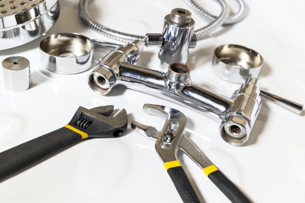 adjustable wrenches and disassembled shower faucet